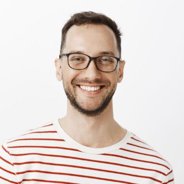 A smiling man wearing glasses and a striped t - shirt.