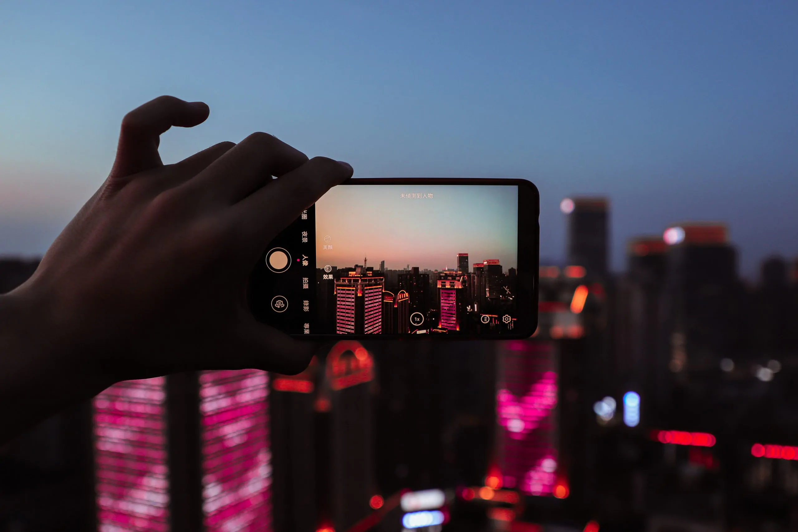 Une personne prenant une photo d'une ville la nuit.