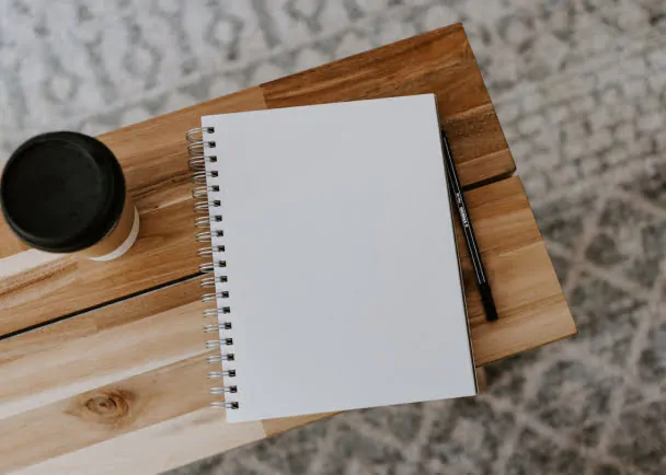 A customized stationery notebook on a wooden table next to a cup of coffee.