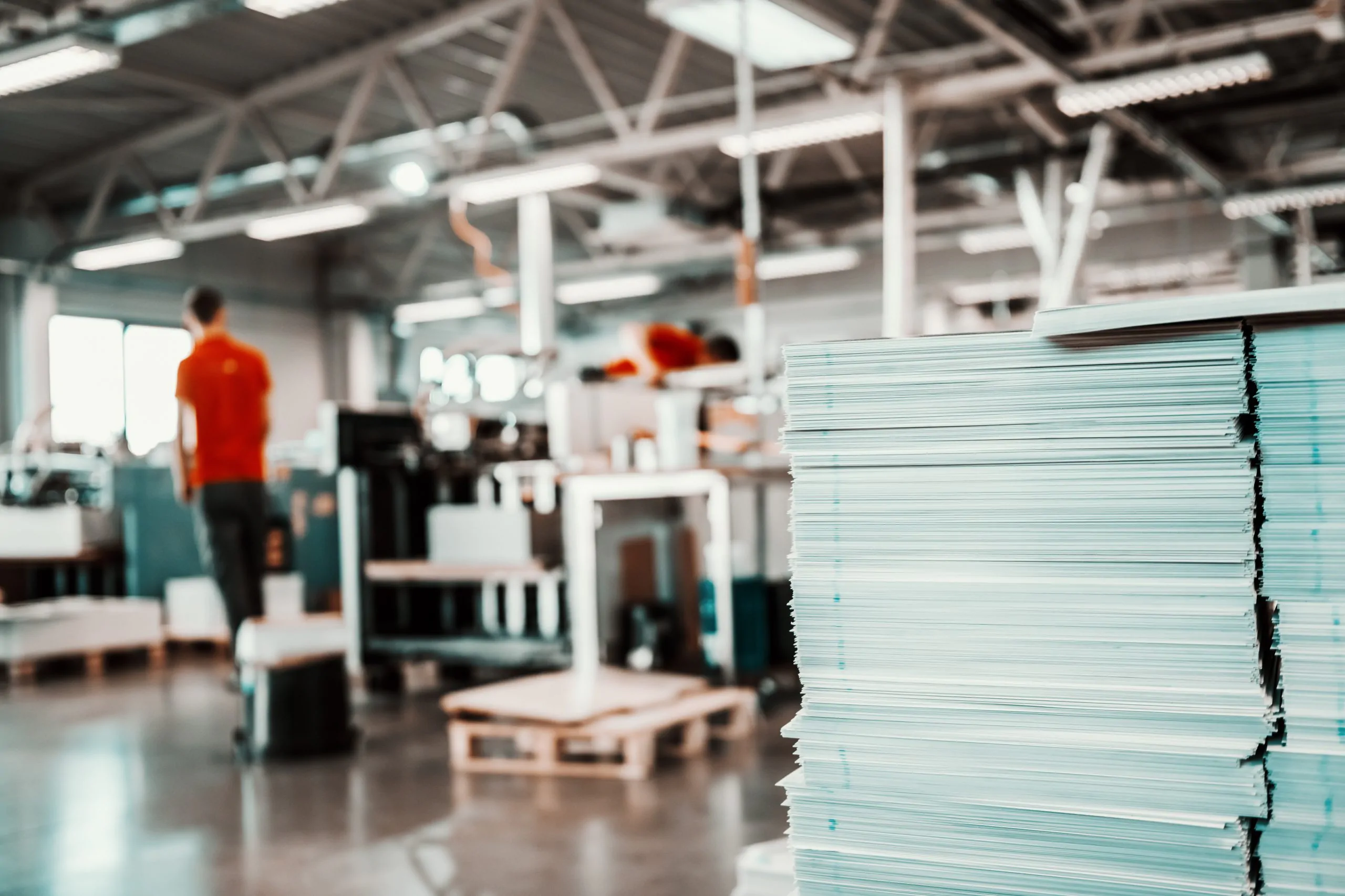 Picture of printing shop interior. Selective focus on pile of sheets.