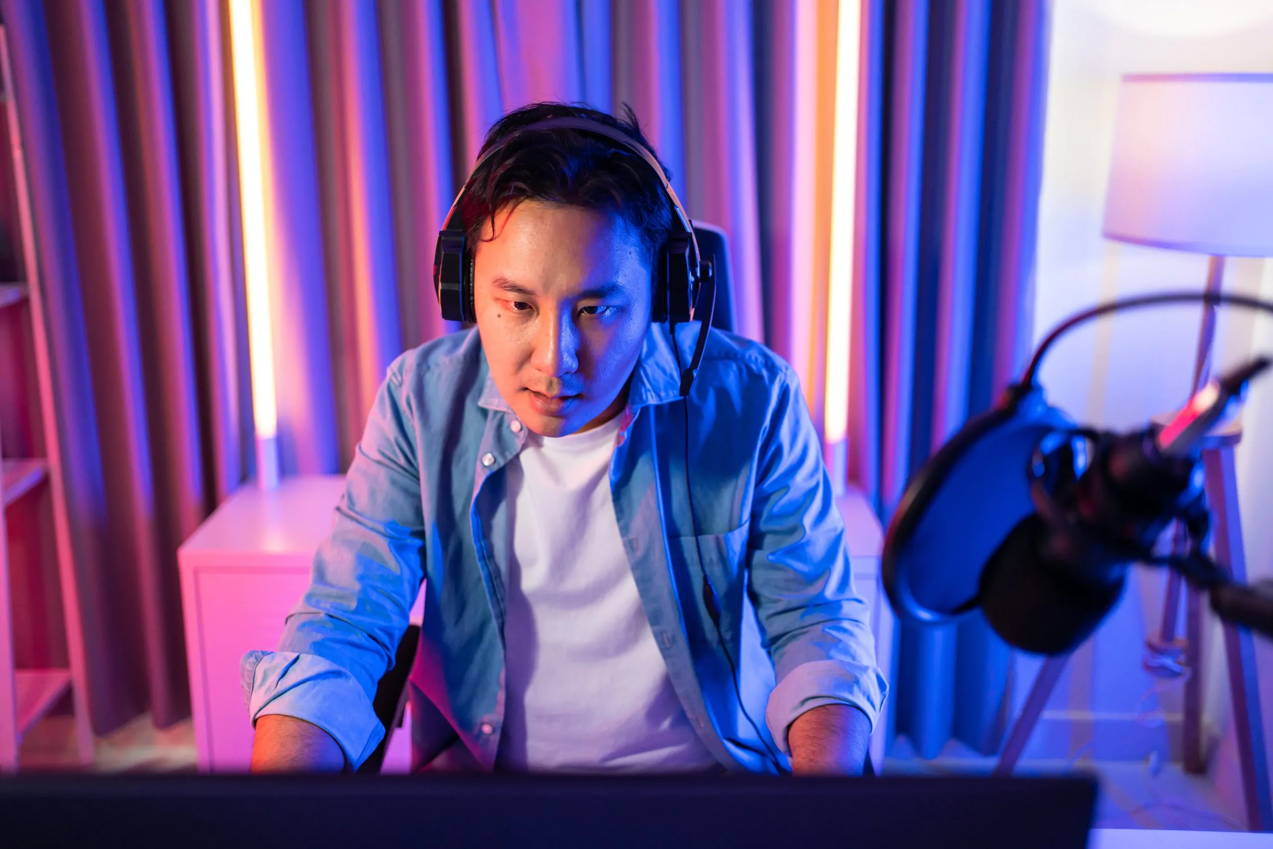 A man sitting at a desk with headphones, a laptop, and focusing on video marketing.