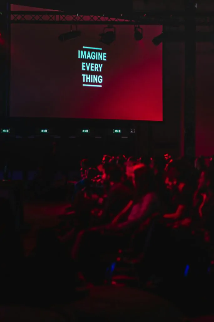 Un groupe de personnes assises dans une salle lors d'un événement d'entreprise avec un grand écran.