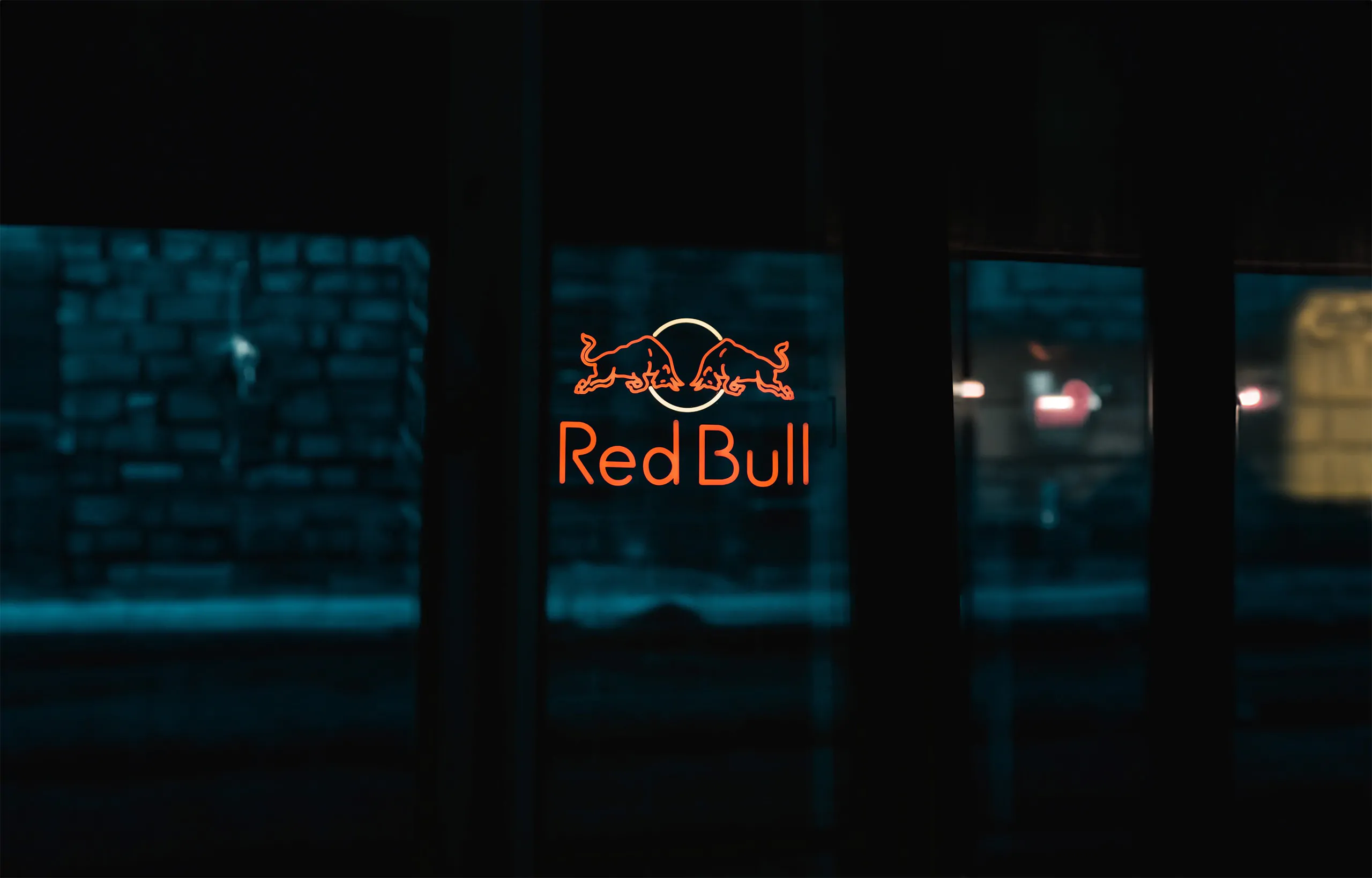 Le logo d'un taureau rouge sur une fenêtre la nuit, éclairé par une agence de marketing.