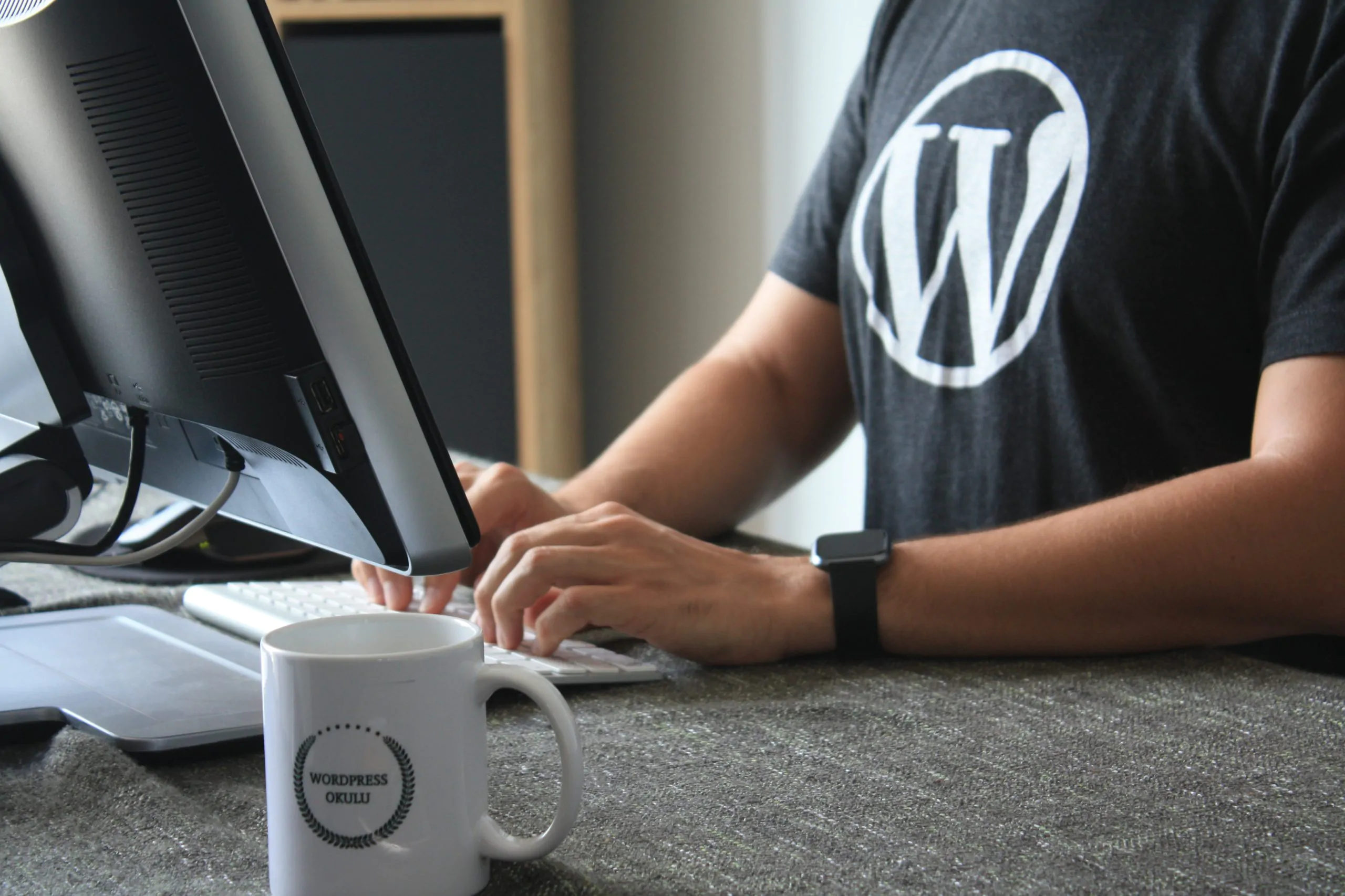 A man typing on a computer with a WordPress web development company logo on it.