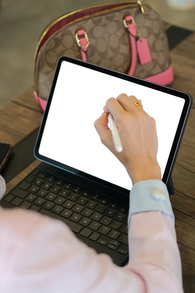 Une femme compose une campagne de marketing par courriel B2B sur un ordinateur tablette avec un stylo blanc.