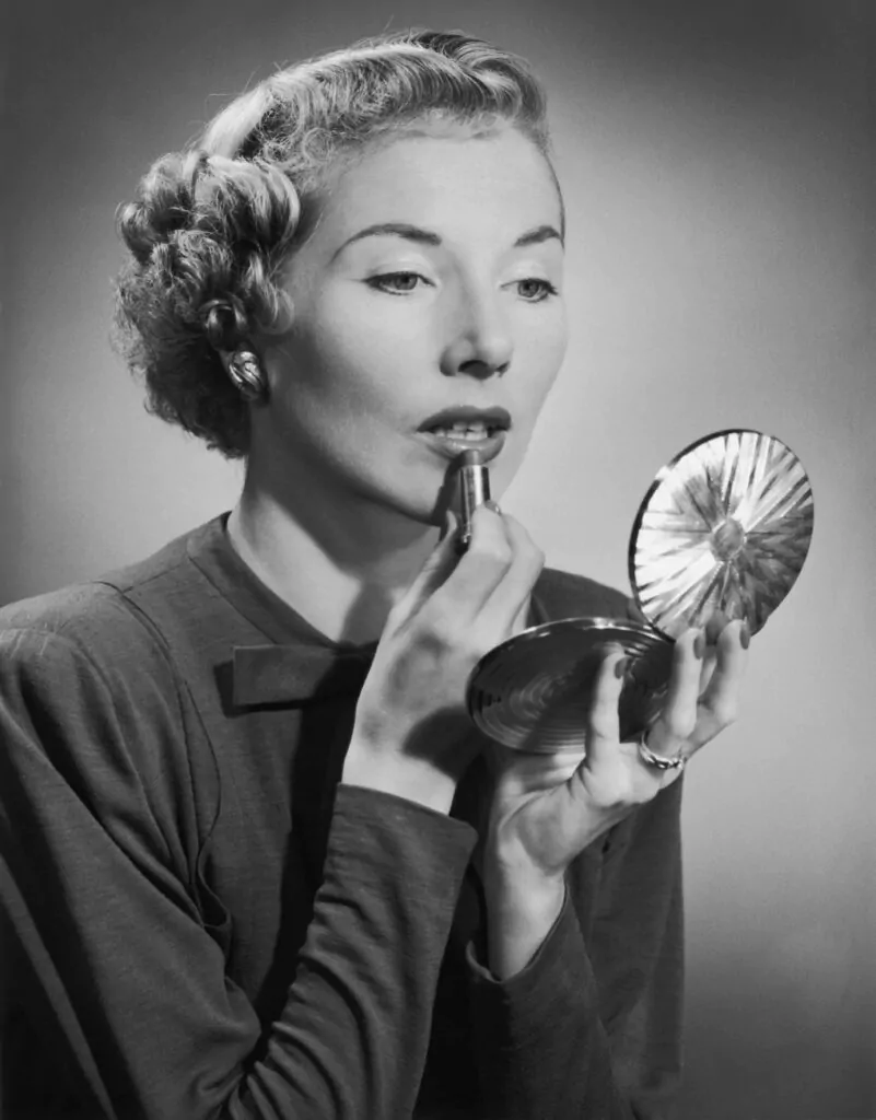 Une femme se met du rouge à lèvres à l'aide d'un miroir numérique.