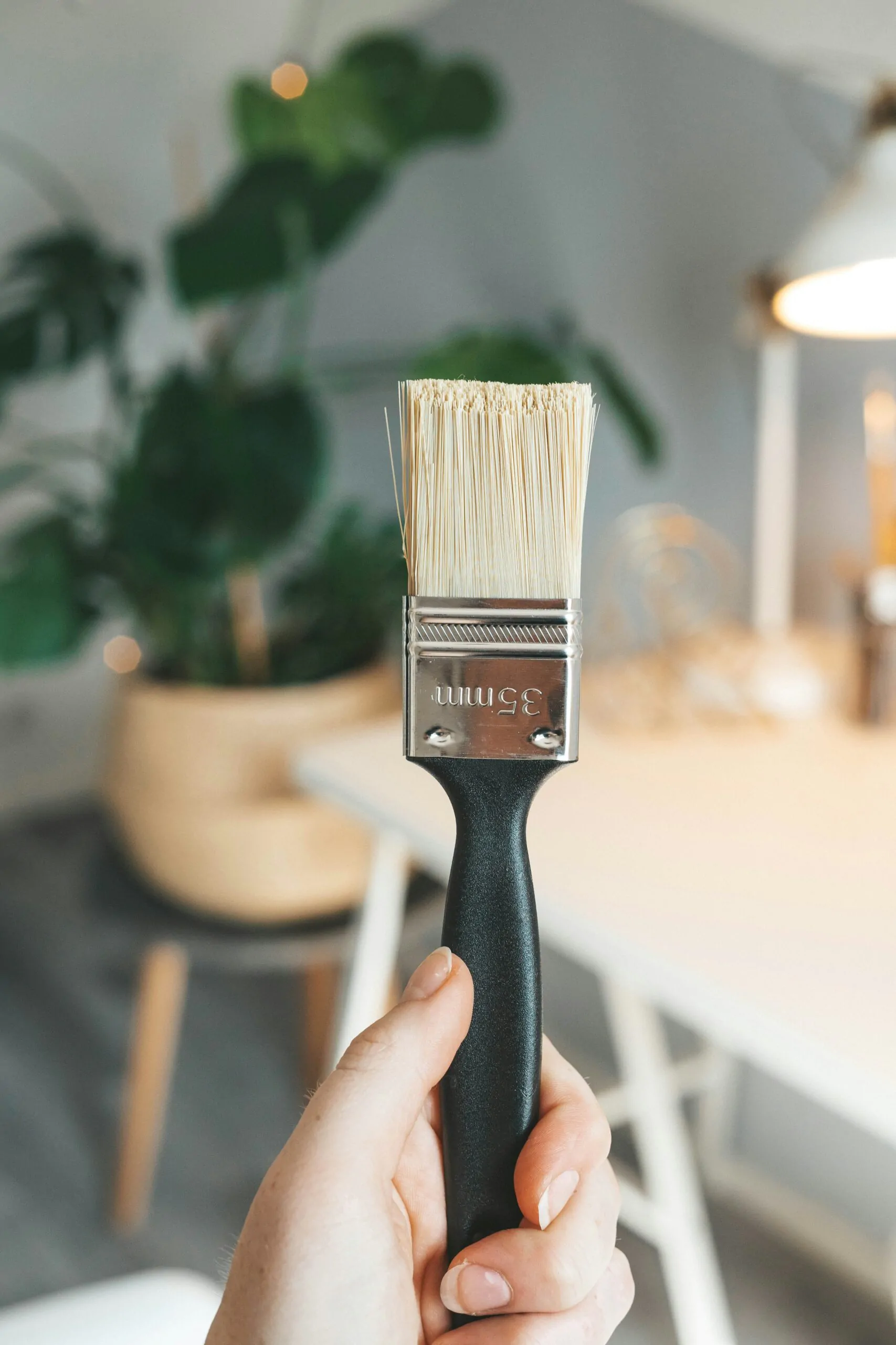 A person holding a paintbrush in front of a plant for a website redesign project.