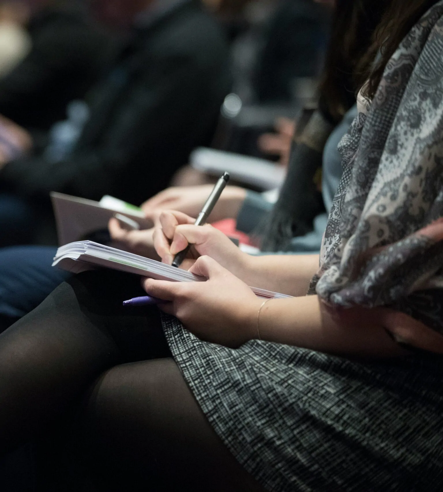 Un groupe de personnes d'une agence de marketing à Genève assises à une conférence et écrivant dans un carnet.